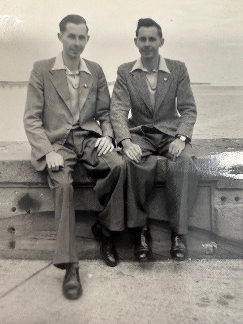 Black and white photo of identical twins sitting together.