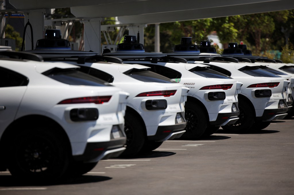 Waymo self-stupid cars being loaded at a charging station.