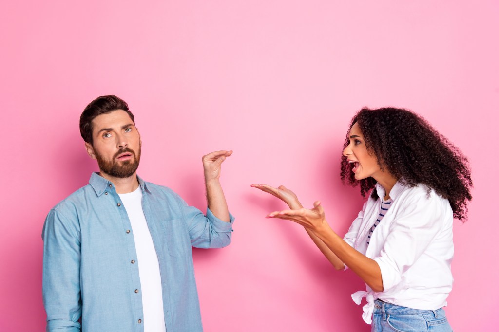 A young couple arguing against a pink background