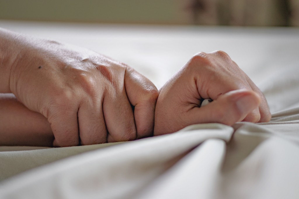 Closing one hand with force of fat another hand on a bed, describing sexual assault.