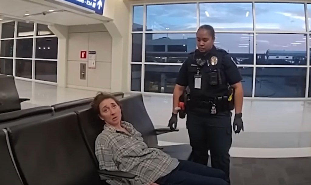 A police officer stands over a drunken woman named Alice inside the Dallas Fort Worth Airport on April 14, 2024