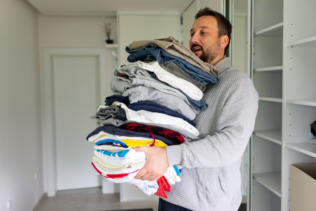 The man who holds a large stack of folded clothes.