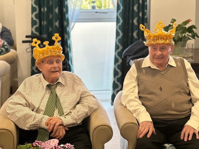 Identical twins celebrating their 100th birthday by wearing inflatable wreaths.